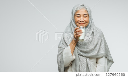 Indonesian grandmother enjoys a glass of milk Indonesian grandmother enjoys a glass of milk 127960260
