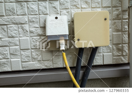 A joint box and waterproof outlet installed on the exterior wall of a detached house A joint box and waterproof outlet installed on the exterior wall of a detached house 127960335