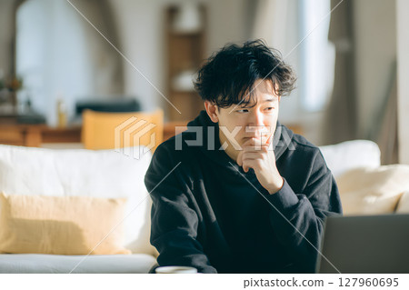 A young Asian man contemplating at home. A moment of relaxation in his daily life 127960695