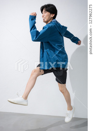 一位身穿運動服的男士全身擺著跑跳姿勢。鍛煉很有趣。 127962275