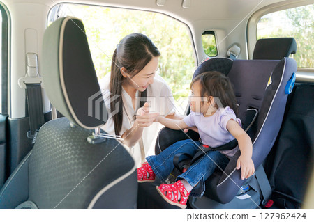 Mom putting her child in a car seat 127962424