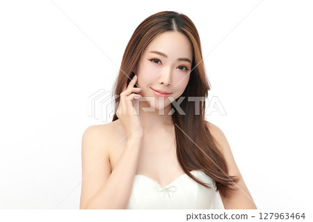 A beautiful young Asian woman with clean, fresh skin against a white background. Skincare, facial treatment, cosmetology, beauty, and spa. An elegant portrait of an Asian woman. 127963464
