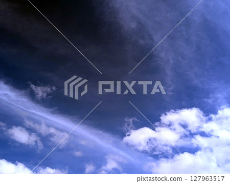 Close up of atmospheric blue black sky with whispy white clouds Close up of atmospheric blue black sky with whispy white clouds 127963517