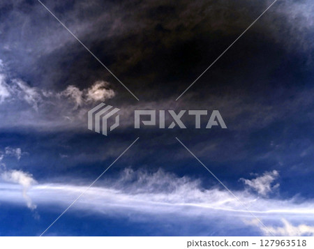 Close up of atmospheric blue black sky with whispy white clouds Close up of atmospheric blue black sky with whispy white clouds 127963518