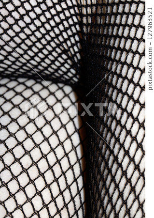 Close up of black fishnet tights on skin legs curves abstract background 127963521