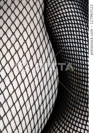 Close up of black fishnet tights on skin legs curves abstract background 127963522