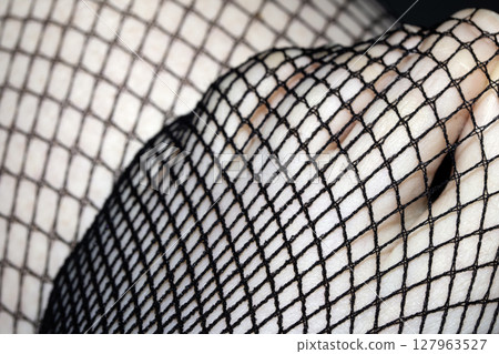 Close up of black fishnet tights on skin legs curves abstract background 127963527