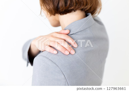 A middle-aged woman in a suit suffering from stiff shoulders 127963661