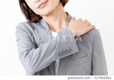 A middle-aged woman in a suit suffering from stiff shoulders 127963662