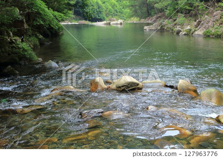 一條河流緩緩流過綠樹環繞的山 127963776