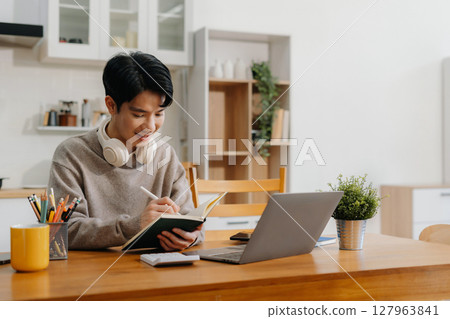 Lifestyle people, using laptop computer and smartphone sitting in the kitchen. Happy male, entrepreneur, small business owner working online at home office. 127963841