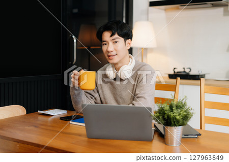 Happy male enjoying work sitting in the kitchen, looking to camera. 127963849
