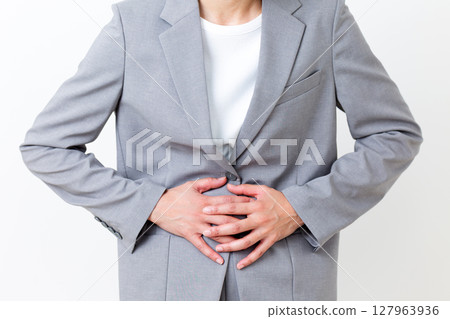 A middle-aged woman in a suit suffering from stomach pain A middle-aged woman in a suit suffering from stomach pain 127963936