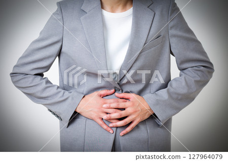 A middle-aged woman in a suit suffering from stomach pain A middle-aged woman in a suit suffering from stomach pain 127964079