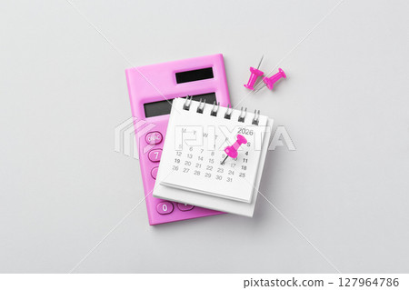 2026 Calendar with pin on date and pink calculator on grey background, financial, budget planning 127964786