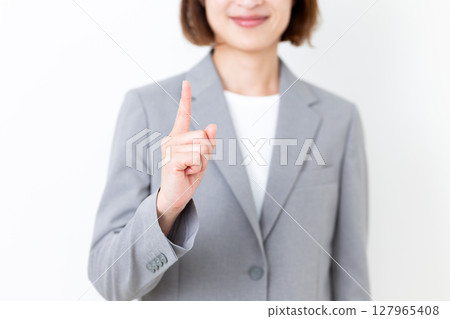 A middle-aged woman in a suit who raises her index finger 127965408