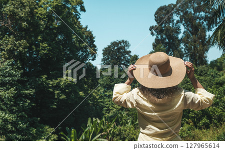 Woman in Straw Hat Admiring Tropical Forest View 127965614