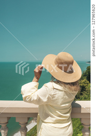 Woman in Summer Hat Looking at Sea Horizon from Cliff 127965620