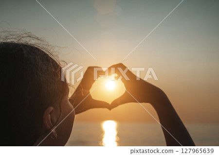 Heart Hands at Sunset Over the Sea 127965639