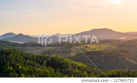 Overlooking the Lusatian Mountains from Popov Cliffs, the landscape showcases lush forests and rolling hills under a vibrant sunset sky, capturing the serene beauty of Czechia and Germany. Overlooking the Lusatian Mountains from Popov Cliffs, the landscape showcases lush forests and rolling hills under a vibrant sunset sky, capturing the serene beauty of Czechia and Germany. 127965713