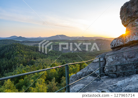 Experience a stunning sunset from the Popov Cliffs, with views of the lush Lusatian Mountains in Czechia and Germany, showcasing nature's beauty in the evening light. 127965714