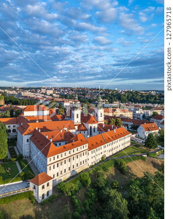 Strahov Monastery captures the serene beauty of Prague at sunrise, with its stunning architecture and surrounding greenery. The aerial view showcases the vibrant rooftops and peaceful atmosphere. Strahov Monastery captures the serene beauty of Prague at sunrise, with its stunning architecture and surrounding greenery. The aerial view showcases the vibrant rooftops and peaceful atmosphere. 127965718