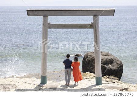 一對夫婦站在海岸邊的鳥居門前 127965775