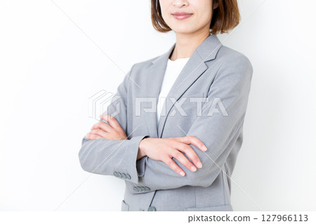 A middle-aged woman in a gray suit with her arms folded A middle-aged woman in a gray suit with her arms folded 127966113