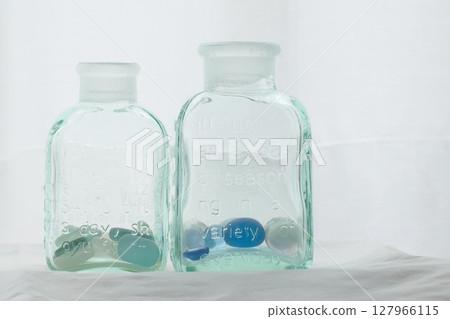 窗邊白色窗簾前有兩個玻璃瓶 窗邊白色窗簾前有兩個玻璃瓶 127966115