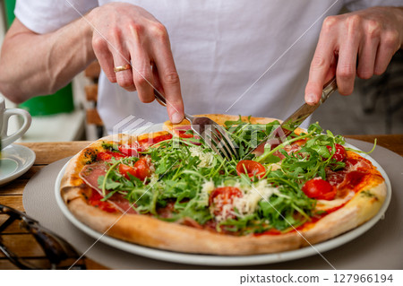 Fresh Italian pizza with arugula, cherry tomatoes, prosciutto and parmesan served at outdoor cafe Fresh Italian pizza with arugula, cherry tomatoes, prosciutto and parmesan served at outdoor cafe 127966194