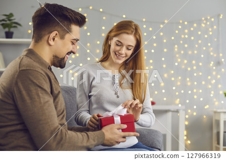 Smiling young woman opening box with birthday or Valentine present from her boyfriend Smiling young woman opening box with birthday or Valentine present from her boyfriend 127966319