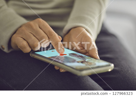 Single woman pressing the like button below attractive man's profile photo on dating app 127966323