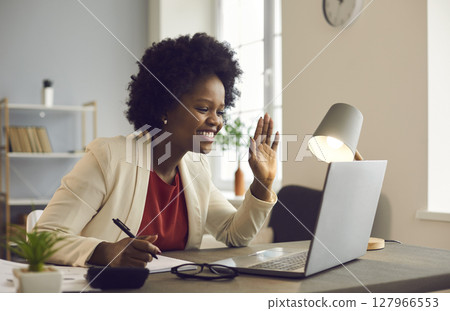 Friendly african american businesswoman holds an online meeting while sitting in the office. Friendly african american businesswoman holds an online meeting while sitting in the office. 127966553