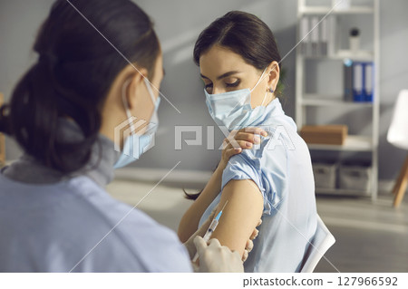Young woman in medical face mask getting vaccine injection during infection outbreak 127966592