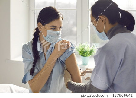 Young woman getting vaccine shot during immunization campaign at clinic or hospital Young woman getting vaccine shot during immunization campaign at clinic or hospital 127966641