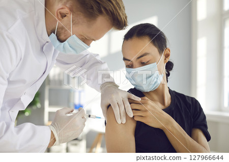 Male patient in medical face mask getting seasonal flu or modern Covid-19 vaccine Male patient in medical face mask getting seasonal flu or modern Covid-19 vaccine 127966644