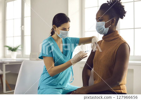African-American woman getting modern flu or Covid-19 vaccine at doctor's office 127966656