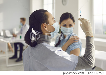 Doctor holding a syringe with medication releasing a stream of medication to get rid of air bubbles. Doctor holding a syringe with medication releasing a stream of medication to get rid of air bubbles. 127966750