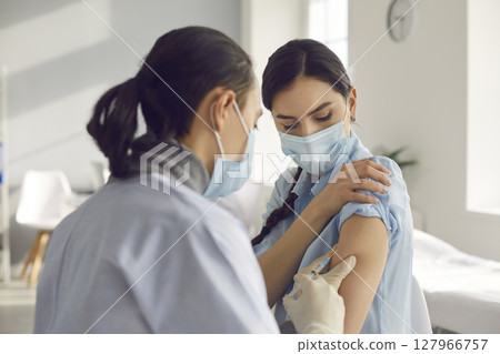 Young woman getting antiviral vaccine injection during seasonal vaccination campaign 127966757