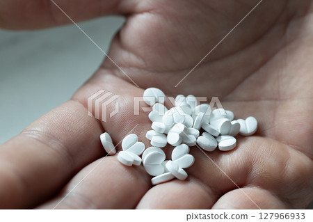 Multiple White Pills Scattered in a Hand Signaling Possible Medication or Supplement Use Multiple White Pills Scattered in a Hand Signaling Possible Medication or Supplement Use 127966933