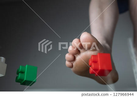 Foot Experiencing Pain Due to Stepping on Construction Toy Blocks in a Household Environment 127966944