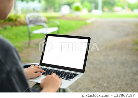 Close up of hands typing on laptop in a natural outdoor, combining productivity and relaxation 127967197
