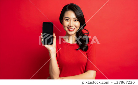 A woman smiling and showing her smartphone screen 127967220
