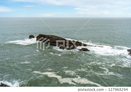 Rocky uninhabited island surrounded by sea 127968294