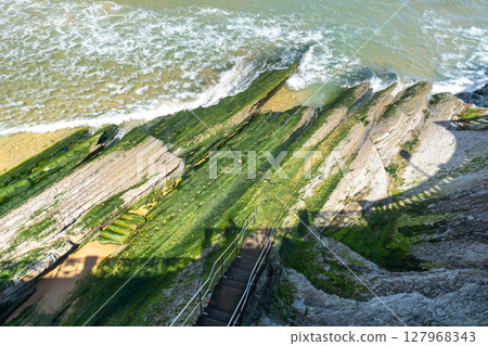 Green algae cover the sloped coastal rocks 127968343