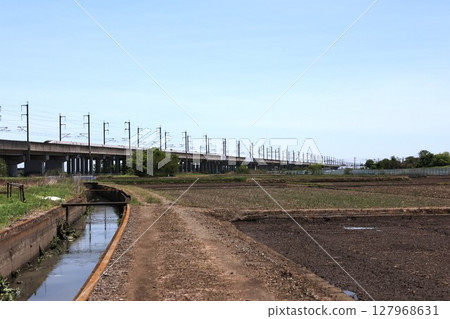 Hokuriku Shinkansen train running through the countryside Hokuriku Shinkansen train running through the countryside 127968631