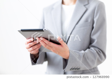 A middle-aged woman in a gray suit holding a tablet 127968990
