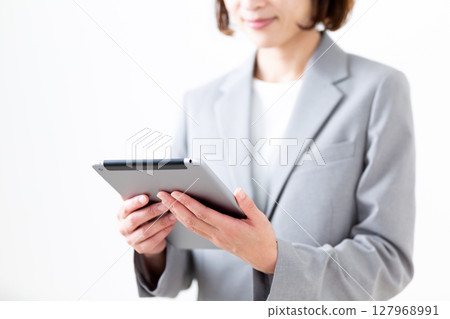 一位身穿灰色西裝的中年婦女拿著平板電腦 127968991