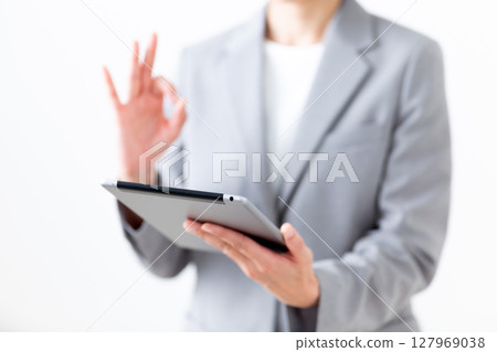 A middle-aged woman in a gray suit holding a tablet and making a circle sign A middle-aged woman in a gray suit holding a tablet and making a circle sign 127969038