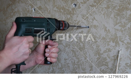 Male hands make hole using electric drill with twist drill bit Male hands make hole using electric drill with twist drill bit 127969226